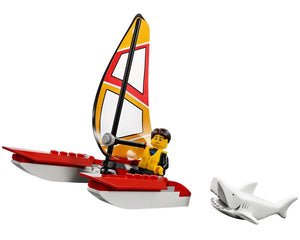 A LEGO minifigure in a yellow life vest pilots a red and white catamaran sailboat with a yellow and red sail. A white LEGO shark swims nearby.