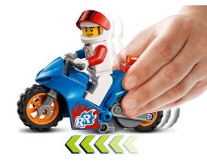 LEGO City 60298 Rocket Stunt Bike, blue pull-back motorcycle with minifigure racer in white suit, red helmet, child's hand pushing.
