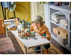 A child plays with the LEGO City 60469 Central Train Station set, featuring a building, forklift, and minifigures.