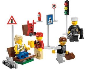 LEGO City 8401 set with various minifigures (police, pedestrian, woman, man with coffee), street signs, traffic light, and a bench.