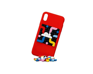 A red phone case featuring a black LEGO Dots 41954 adhesive patch with a vibrant custom pattern. Loose LEGO Dots are at the base.