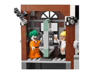 LEGO Joker in orange prison uniform and Harley Quinn in lab coat inside an Arkham Asylum build, with cameras.