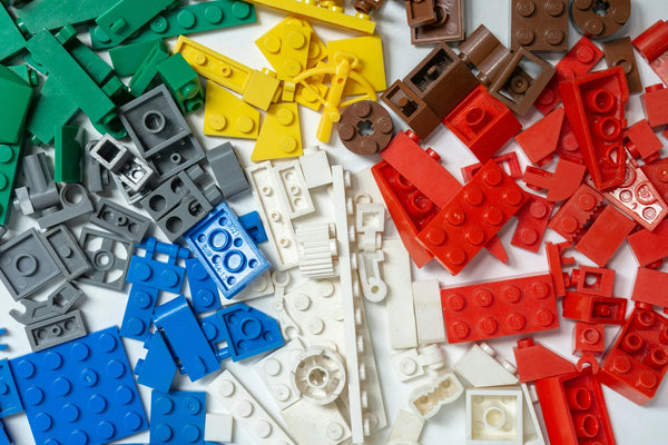 Kleurrijke LEGO onderdelen gesorteerd per kleur op een witte achtergrond