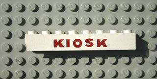 White LEGO 1x8 brick with red 'KIOSK' text, positioned on a grey LEGO baseplate.