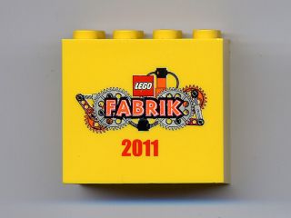 Yellow LEGO 2x4x3 brick with 'LEGO FABRIK 2011' logo featuring gears and chains printed on one side.