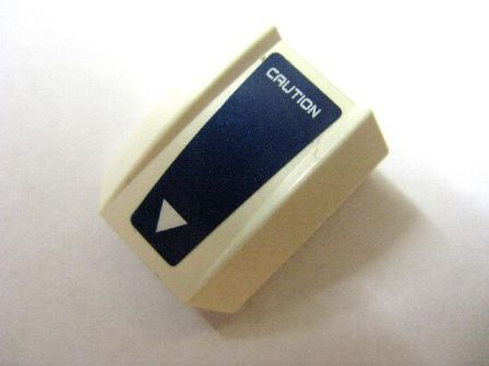 White LEGO curved 2x2 slope with dark blue sticker featuring 'CAUTION' text and a white triangle.