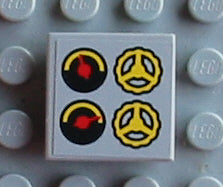 A light gray 2x2 LEGO tile with a sticker featuring two black and yellow gauges with red needles and two yellow steering wheels.
