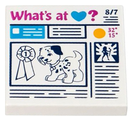 White LEGO 2x2 tile with a newspaper pattern featuring 'What's at Heart?' headline, a spotted dog, and a prize ribbon.