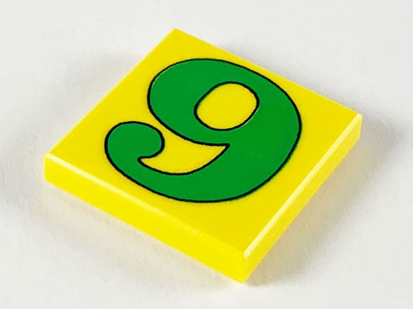 Yellow LEGO 2x2 tile with a green number 9 (or 6) outlined in black on a white background.