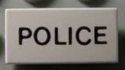Close-up of a white LEGO 1x2 tile featuring the word 'POLICE' printed in black capital letters.