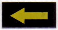 LEGO 3069pb0017 black 1x2 tile with a yellow left-pointing long arrow pattern.