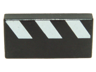 Close-up of a LEGO 3069px15 black 1x2 tile featuring a white diagonal partial stripes pattern.