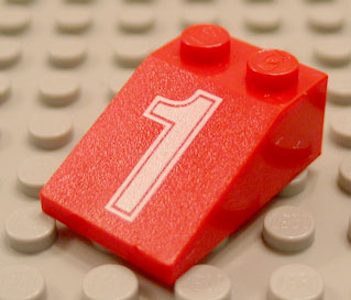 Close-up of a red LEGO 33-degree slope brick, 3x2, with a white number 1 pattern, resting on a gray baseplate.