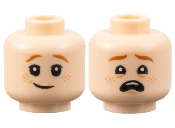 Two light nougat LEGO minifigure heads with dark orange eyebrows and nougat freckles. One side has a lopsided grin, the other a scared open mouth.