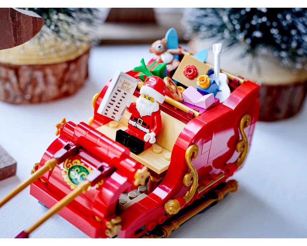 LEGO Santa's Sleigh (40499) with Santa minifigure, a nice list, and gifts, set against a blurry festive background.