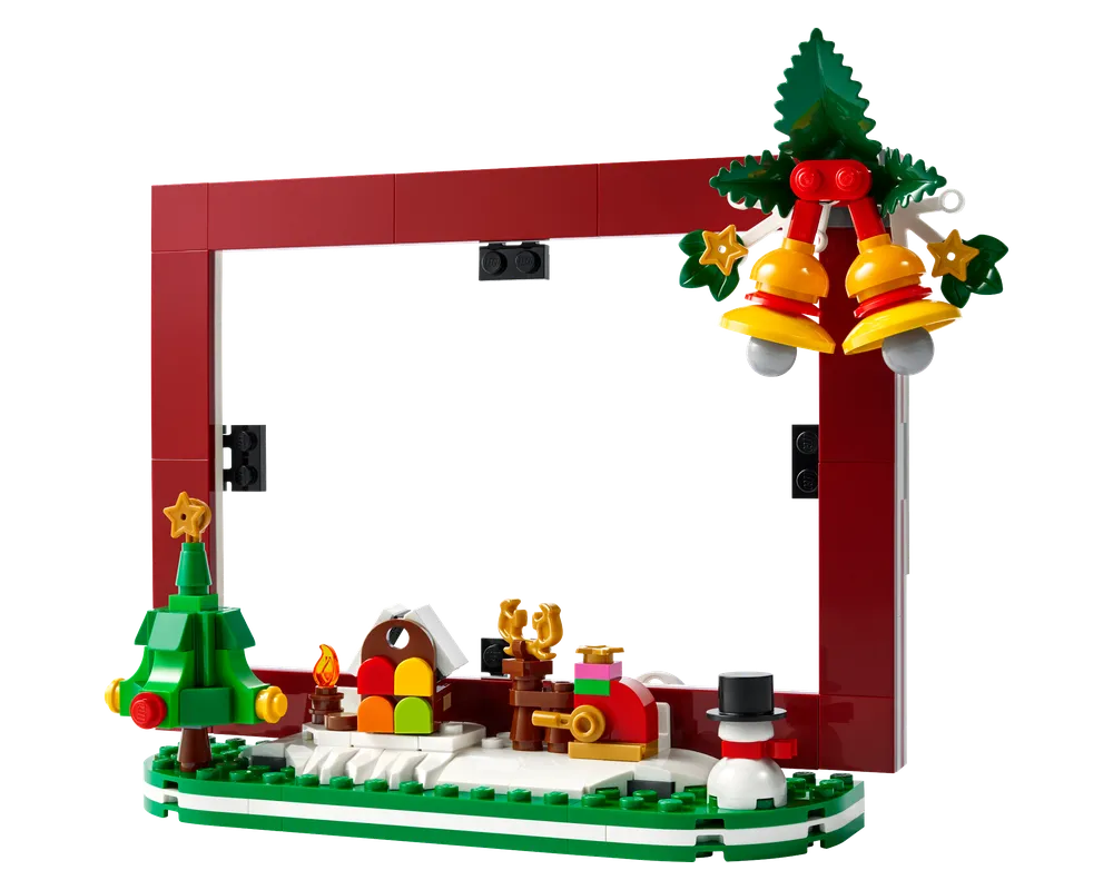 LEGO Christmas picture frame featuring a red frame, snowy base with a Christmas tree, colorful house, reindeer, snowman, and hanging bells.
