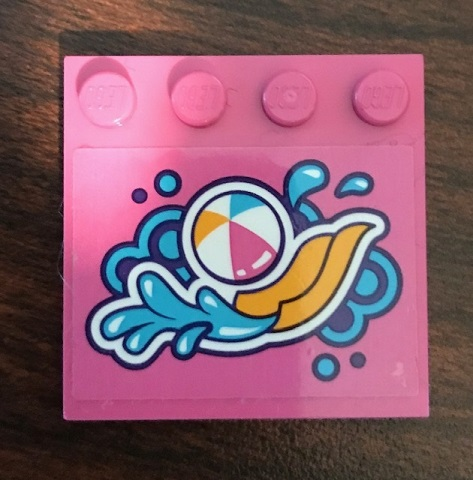 Pink LEGO 4x4 tile with studs on edge and a sticker of a beach ball, water splashes, and a yellow slide pattern.