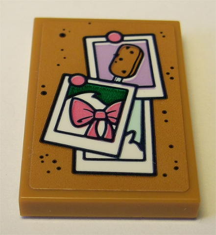LEGO 2x3 tan tile with a cork board pattern featuring pinned photos of a pink bow and a brown ice pop.