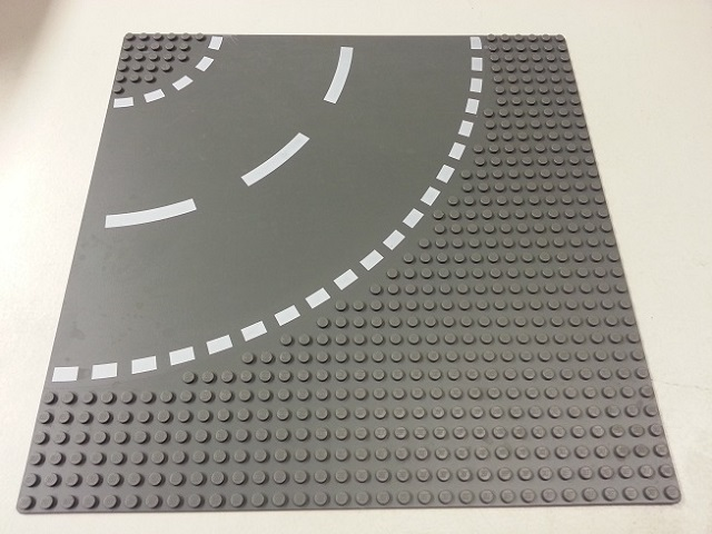 Grey LEGO 32x32 road baseplate, part 44342px2, featuring a 6-stud curve pattern with white dashed lines and two inner solid lines.