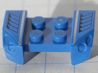 A blue LEGO 2x4 mudguard piece with headlights overhangs, featuring a black grille and silver stripe pattern on both sides.