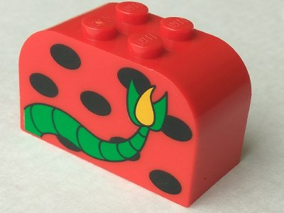 Red curved LEGO Duplo brick with black spots and a green monster tail with a yellow flame tip.