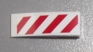 White LEGO curved 3x1 slope with red and white diagonal danger stripes pattern sticker.