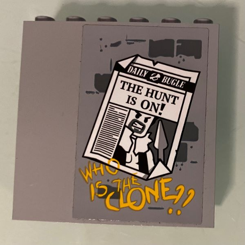 Gray LEGO panel 1x6x5 with 'DAILY BUGLE' newspaper sticker showing 'THE HUNT IS ON!' headline and 'WHO IS THE CLONE??' text.