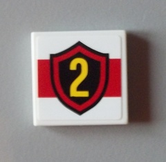 White LEGO 2x2 tile with a red stripe and a black shield featuring a yellow number 2.