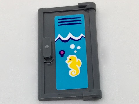A LEGO 60614pb005R dark gray door piece with a vertical handle. It has a blue sticker showing white waves, bubbles, and a yellow seahorse.