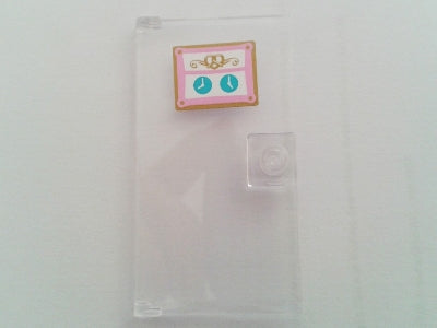 A LEGO 1x4x6 clear door with a stud handle and a sticker featuring two blue clocks and a pretzel design.