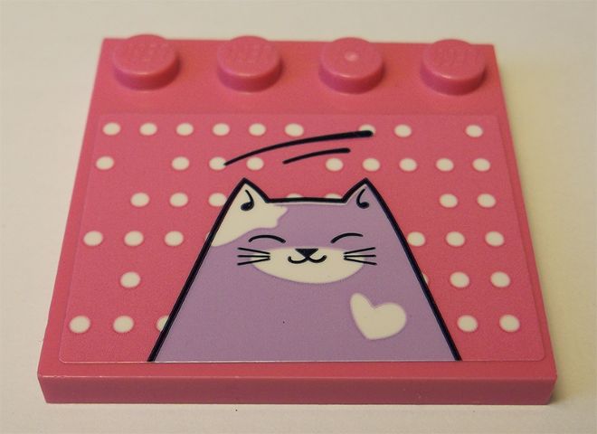 Pink LEGO 4x4 tile with studs on edge, white polka dots, and a lavender cat sticker with white heart and closed eyes.