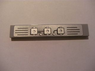 Light gray LEGO 1x6 tile with a metallic sticker depicting an engine block pattern with three squares and grilles.