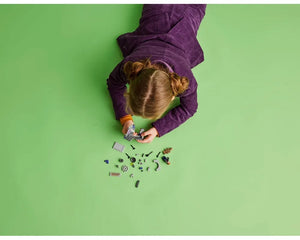 Overhead view: Child in purple plays with LEGO Super Heroes 76253 Guardians of the Galaxy Headquarters on a green floor.