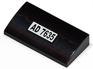 Black LEGO curved slope 2x4x2/3 piece with a white sticker displaying 'AD 7635'.