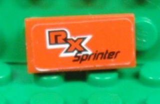 Orange LEGO 1x2 tile with white and black 'RX Sprinter' pattern sticker, displayed on a green LEGO baseplate.
