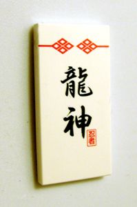 White LEGO 2x4 tile (87079pb0018) with black '龍神' (Dragon God) logogram pattern, red decorative border, and a small red stamp.