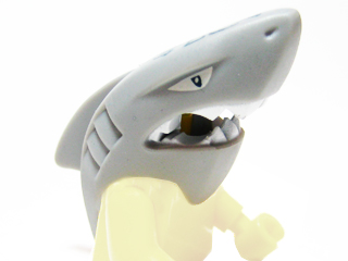 Light grey LEGO minifigure shark head accessory with white eyes, sharp teeth, dark blue splotches, open mouth, and a dorsal fin.