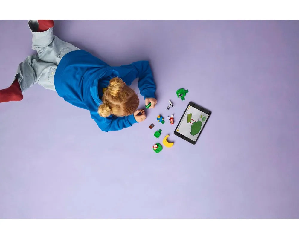A child builds LEGO Animal Crossing Stargazing with Celeste set, looking at a tablet on a light purple background.