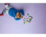 A child builds LEGO Animal Crossing Stargazing with Celeste set, looking at a tablet on a light purple background.