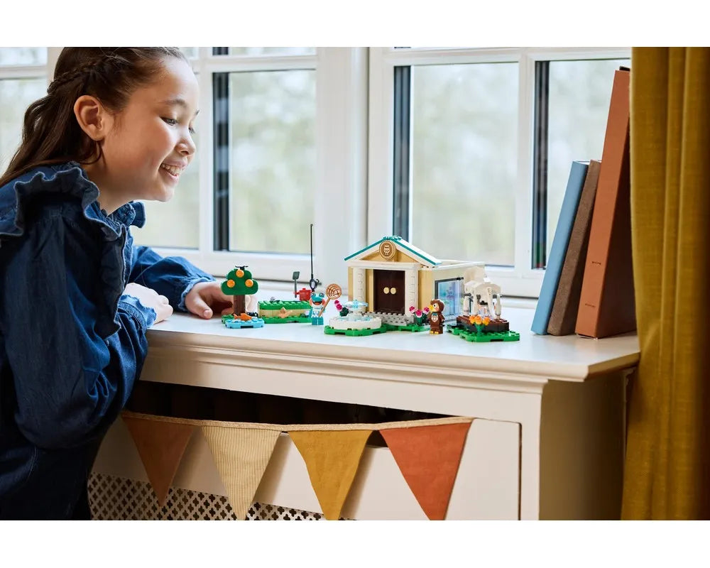 Girl admiring LEGO Animal Crossing 77056 Blathers's Museum Collection set on a white dresser by a window.
