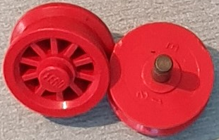 Two red LEGO bb0019 spoked 2x2 wheels with stud. One shows spokes, the other the metal stud and engraved numbers.