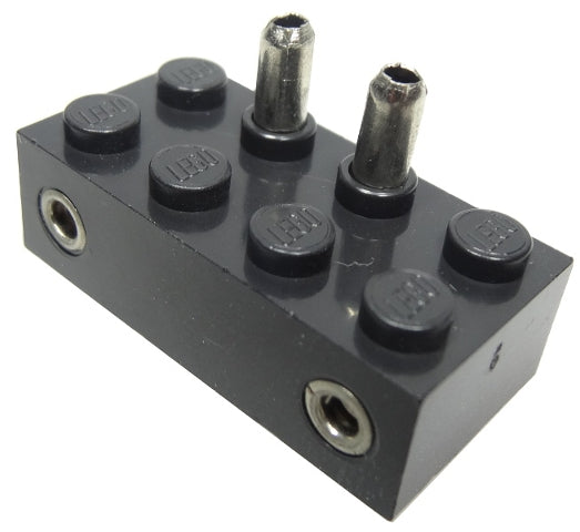A black LEGO 2x4 electric switch brick with two metal pins on top and two metal sockets on the sides for train 4.5V.