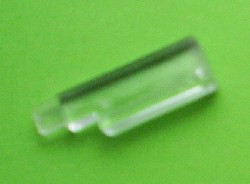 A translucent clear LEGO bb0300 Garage Door Counterweight without Hinge Pin on a green background.