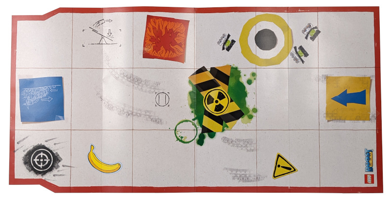 LEGO BOOST paper test mat with red border, grid, and various symbols like targets, hazards, arrows, and a banana.