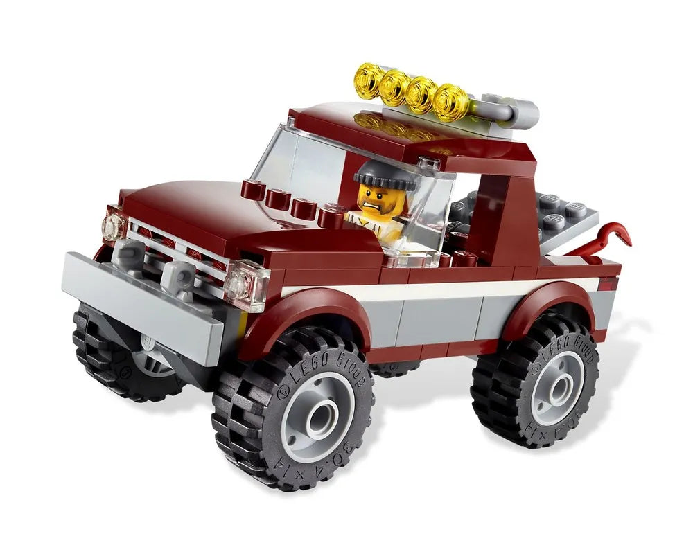 Dark red LEGO pickup truck with a minifigure driver, yellow roof lights, a grey bumper, and off-road tires.