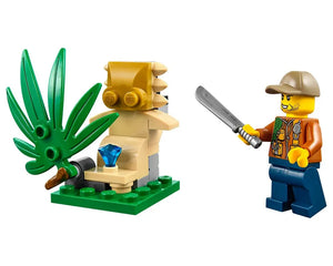 LEGO minifigure explorer with a machete standing next to a tan jungle ruin with a blue gem and large green plant.