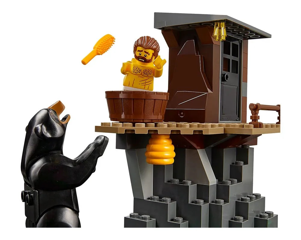 A LEGO set with a shirtless minifigure in a tub on a mountain, surprised by a black bear reaching towards him. A beehive hangs below.