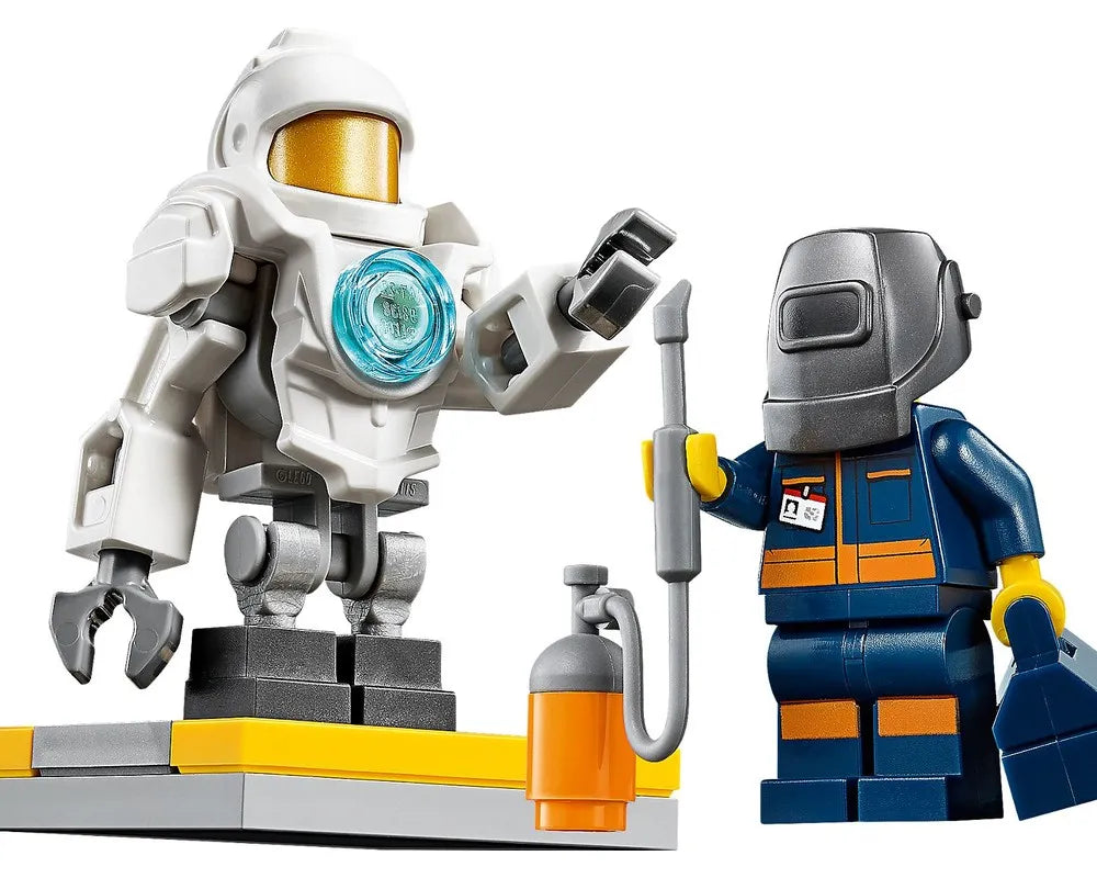 LEGO City 60230 set featuring a white robot with a gold visor on a platform, and a welder minifigure with a torch.