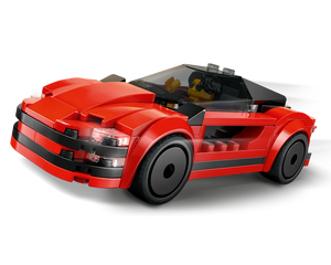 A red LEGO sports car with a minifigure driver, black accents, transparent windshield, and headlights, viewed from the front-right.
