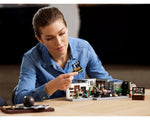 Woman building the LEGO Creator 10291 Queer Eye The Fab 5 Loft set, holding a small piece over the model.